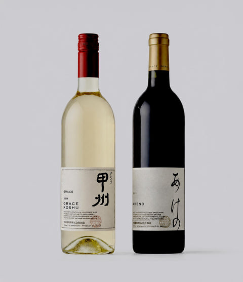 Two wine bottles from Grace Wine, one white and one red, on a light gray background